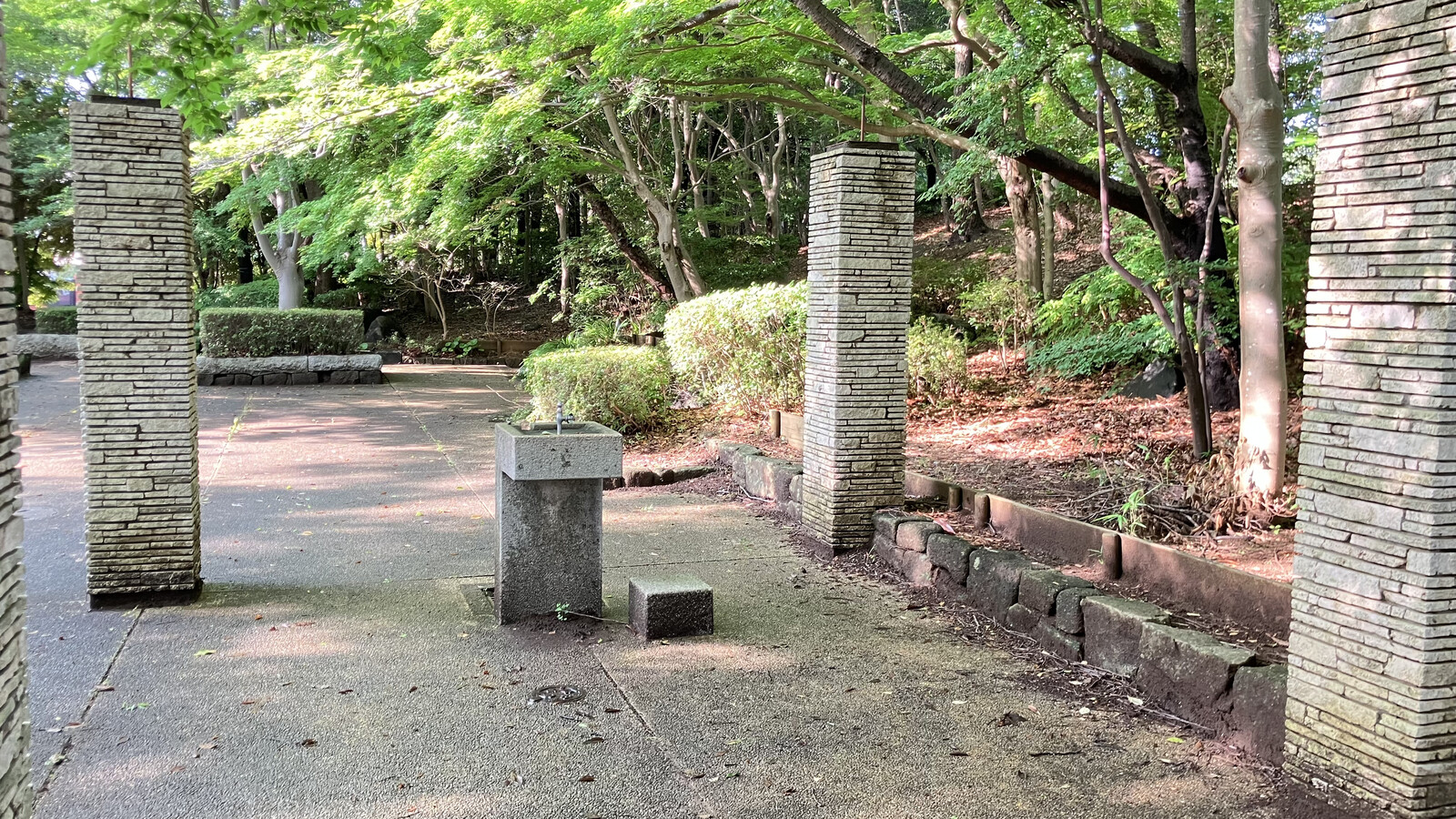 飯綱近隣公園のエントランスに並ぶ石積みの柱と水飲み場